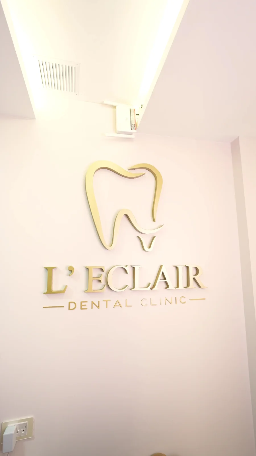 Logo dorado de L’Eclair Dental Clinic en la recepción